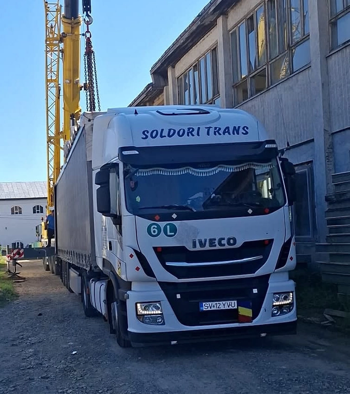 Camion Iveco si semi-remorca cu prelata asteptand sa fie descarcate de marfurile transportate la destinatie